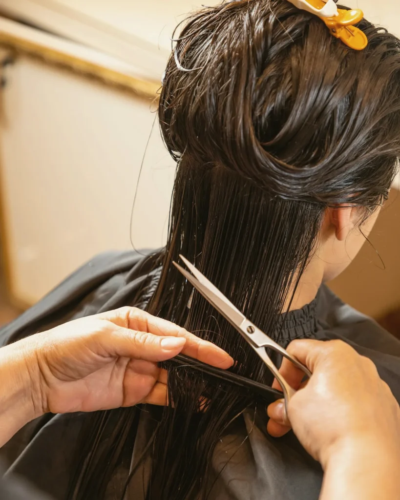 Estilista cortando el pelo mojado con tijera y peine