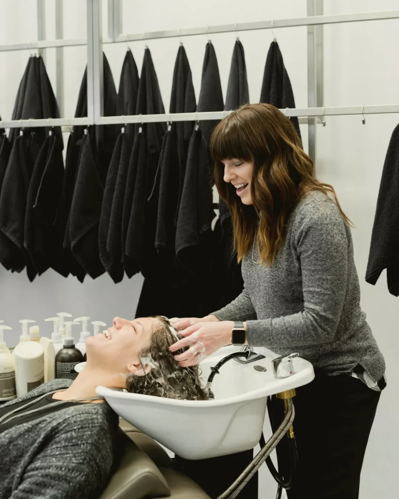 Stylistin wäscht einer Kundin am Waschbecken die Haare